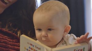 Parent and baby looking at a book.