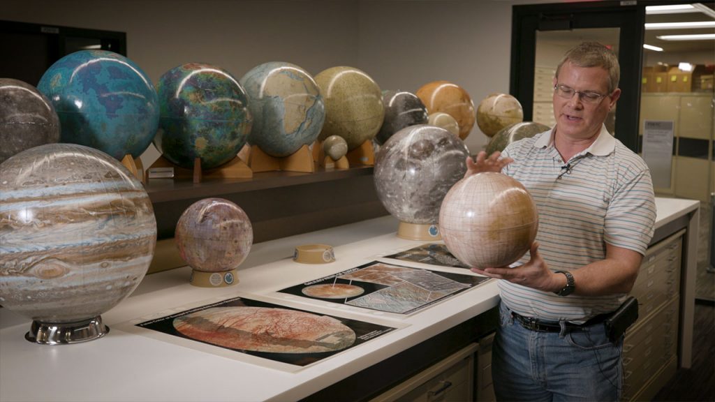Man holding up and describing a globe
