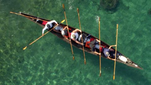 A group of people rowing a ti’at, a traditional Tongva canoe