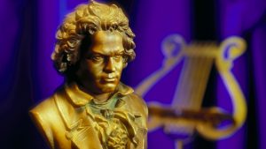 A gold bust of Beethoven sits in front of a music stand