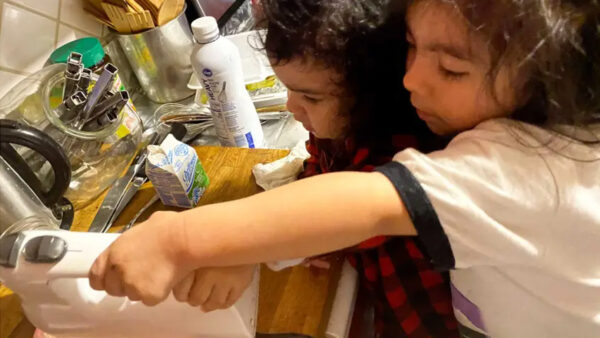 Two kids using a mixer in the kitchen