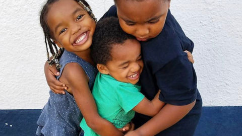 Two older siblings hug their little brother, who has autism.