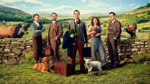 The cast of All Creatures Great and Small stands in a green field.