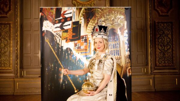 Lucy Worsley sits on a throne, wearing a crown and holding a scepter in Royal Photo and Royal Palace