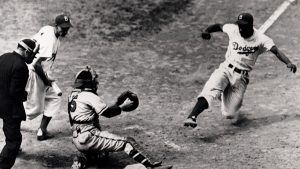 A black and white photo of a baseball player sliding in to home plate