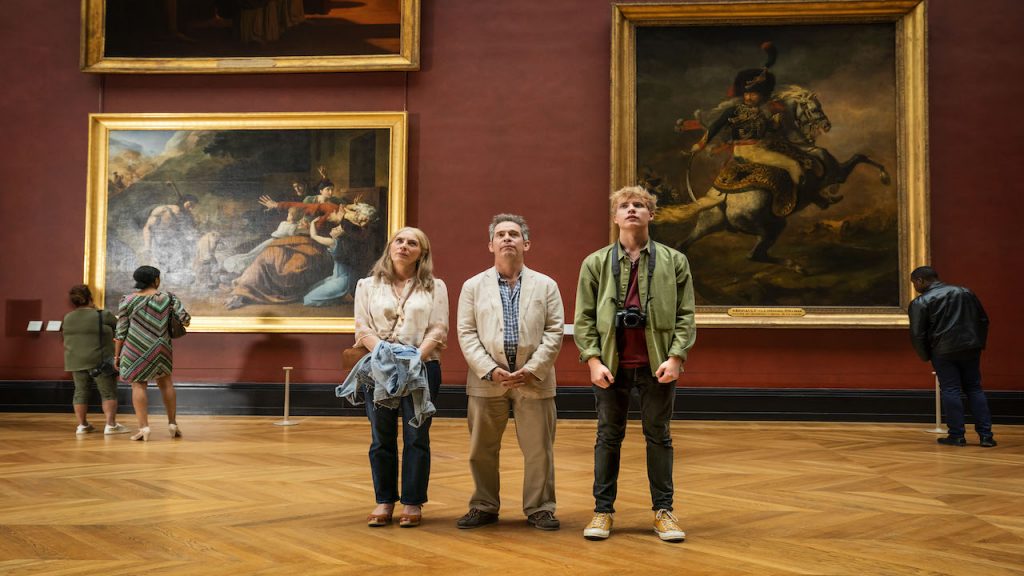 A middle aged couple and their son stand together in an art museum