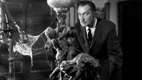 Still from The House on Haunted Hill showing a man next to an ornate bannister covered in cobwebs