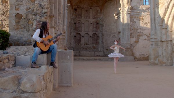 Benise sits on an old stone wall to play his guitar