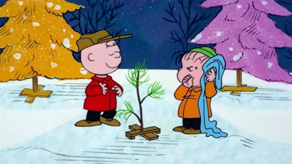 Charlie Brown and linus stand next to the christmas tree