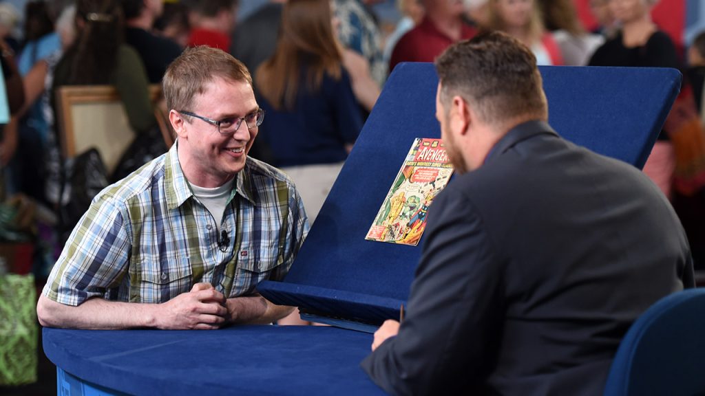 A man sits next to his copy of the Avengers comic book