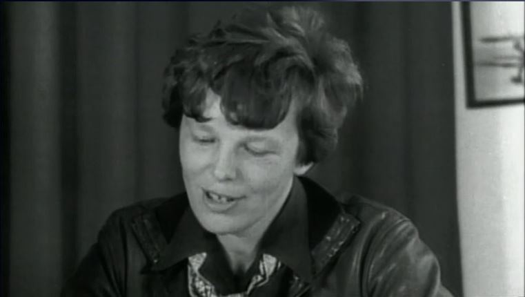 Amelia Earhart speaking into a microphone at a press conference
