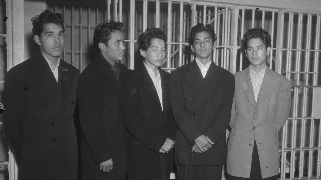 Chicano teens wearing zoot suits in front of cell