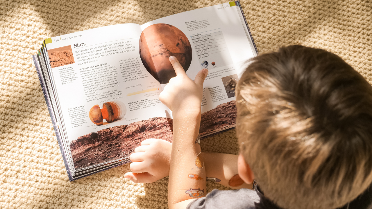 A kid reading a book about Mars