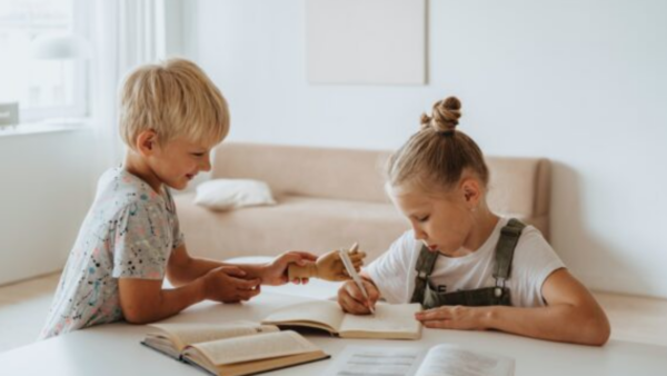 young girl and boy have books, pencil, and paper