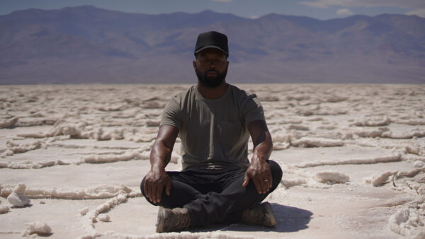 Baratunde sitting criss-cross in the desert