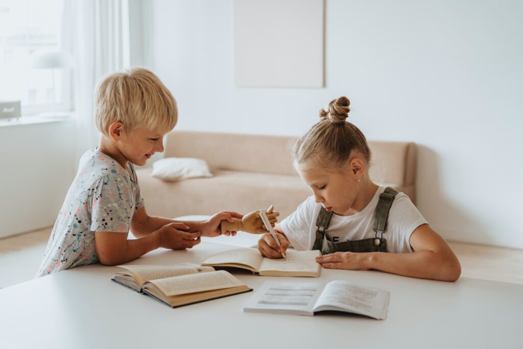 young girl and boy have books, pencil, and paper