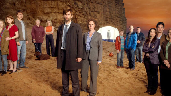 the cast of broadchurch on the beach in front of a cliff
