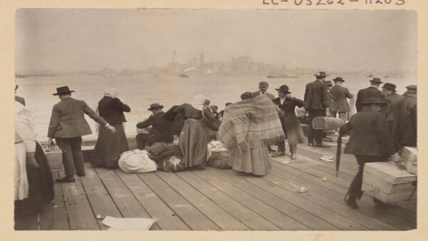 Photo shows immigrant family looking at Statue of Liberty from Ellis Island.