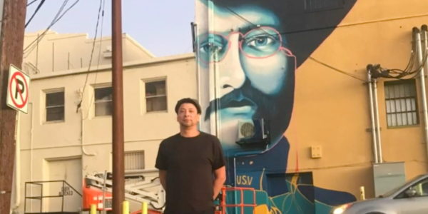Muralist Tato Caraveo with one of his murals in the background