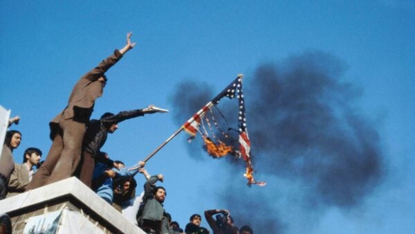 Iranians burn the American flag on the roof of the occupied U.S. embassy. June 1980.