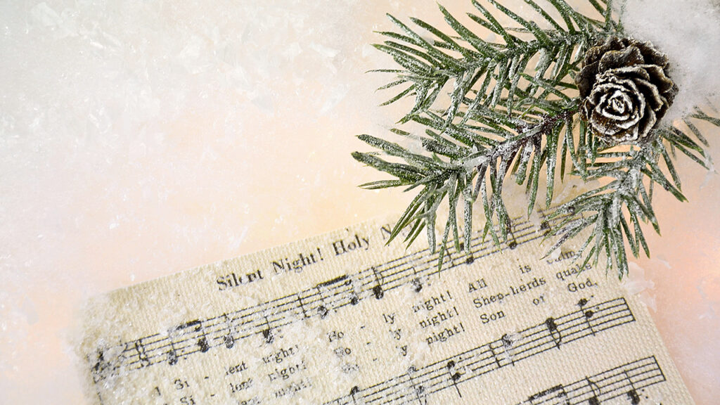 frosted pine cone and greenery on silent night sheet music