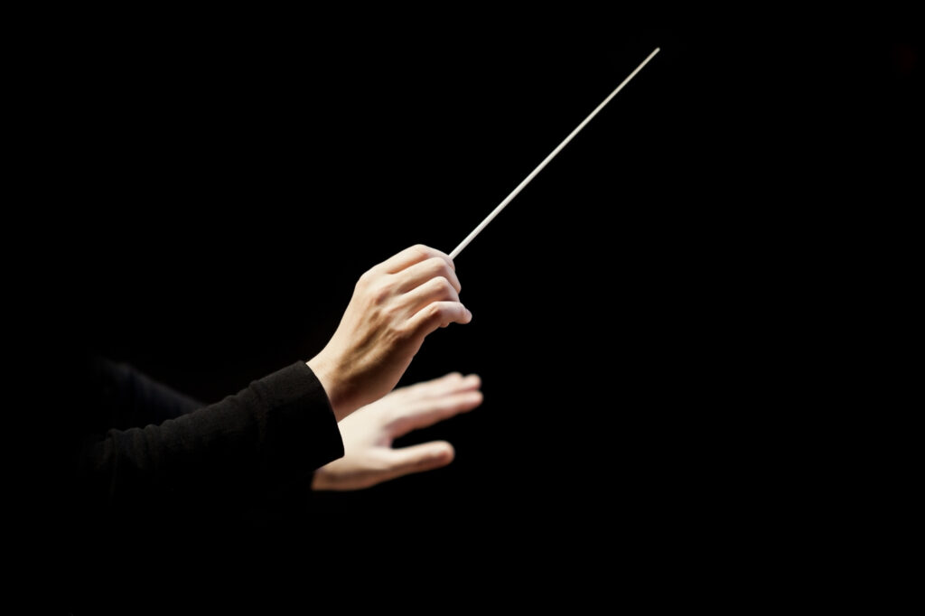 A conductor's hands are in the center, with the right hand holding a baton