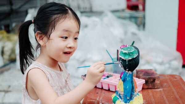 A young girl paints a figurine