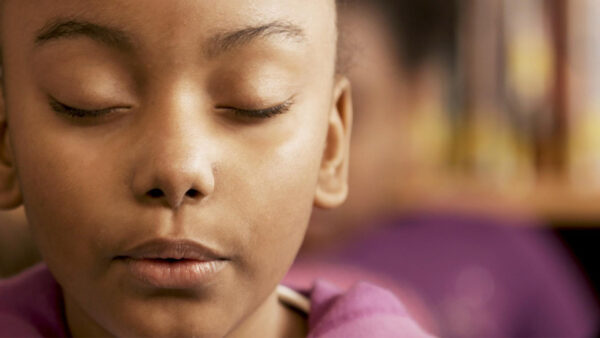 A young girl meditates in class