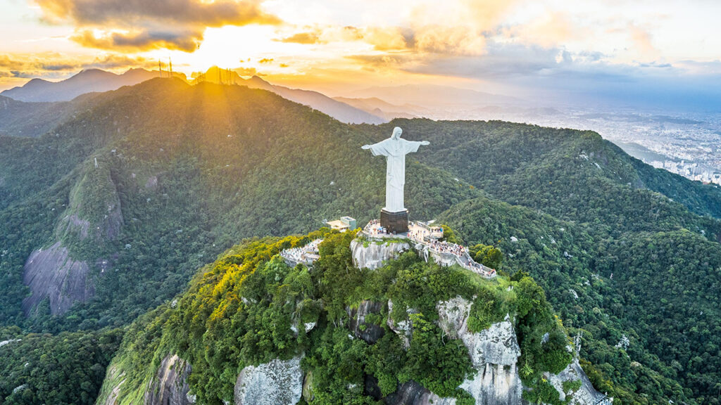Christ the Redeemer statue in Brazil with sunset over the mountains