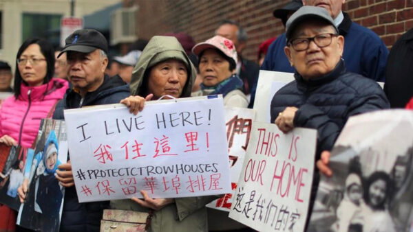 Chinese Americans hold protest signs opposing urban development and gentrification