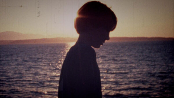 A still image of a boy walking alone along the beach from the special 