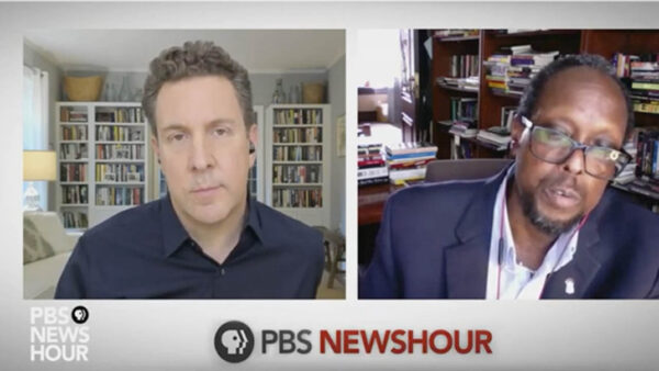 A journalist and a professor side-by-side during an interview on PBS NewsHour
