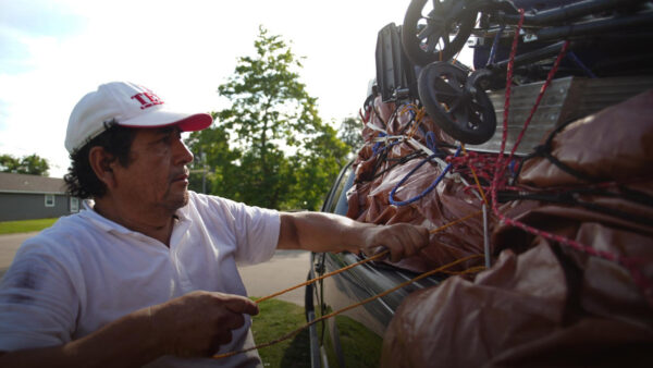 Luciano, a maletero, ties down goods in a truck so he can deliver them to family members