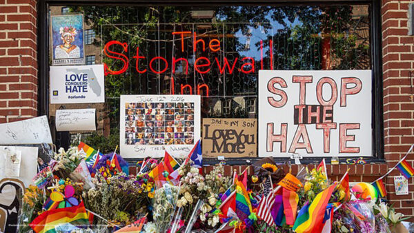 Stonewall Inn with flags, flowers, candles, and signs decorating the front window