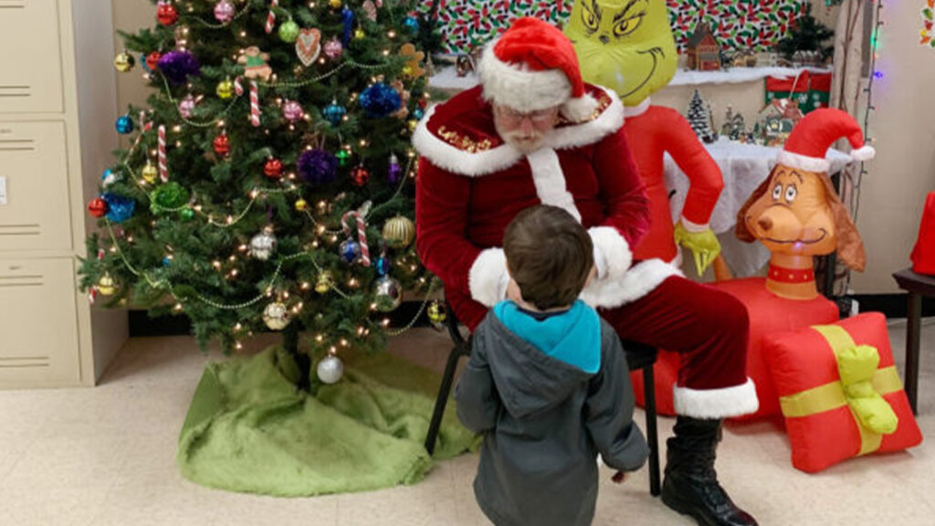 Papa Claus gives a present to a child at Safe House Shelter.