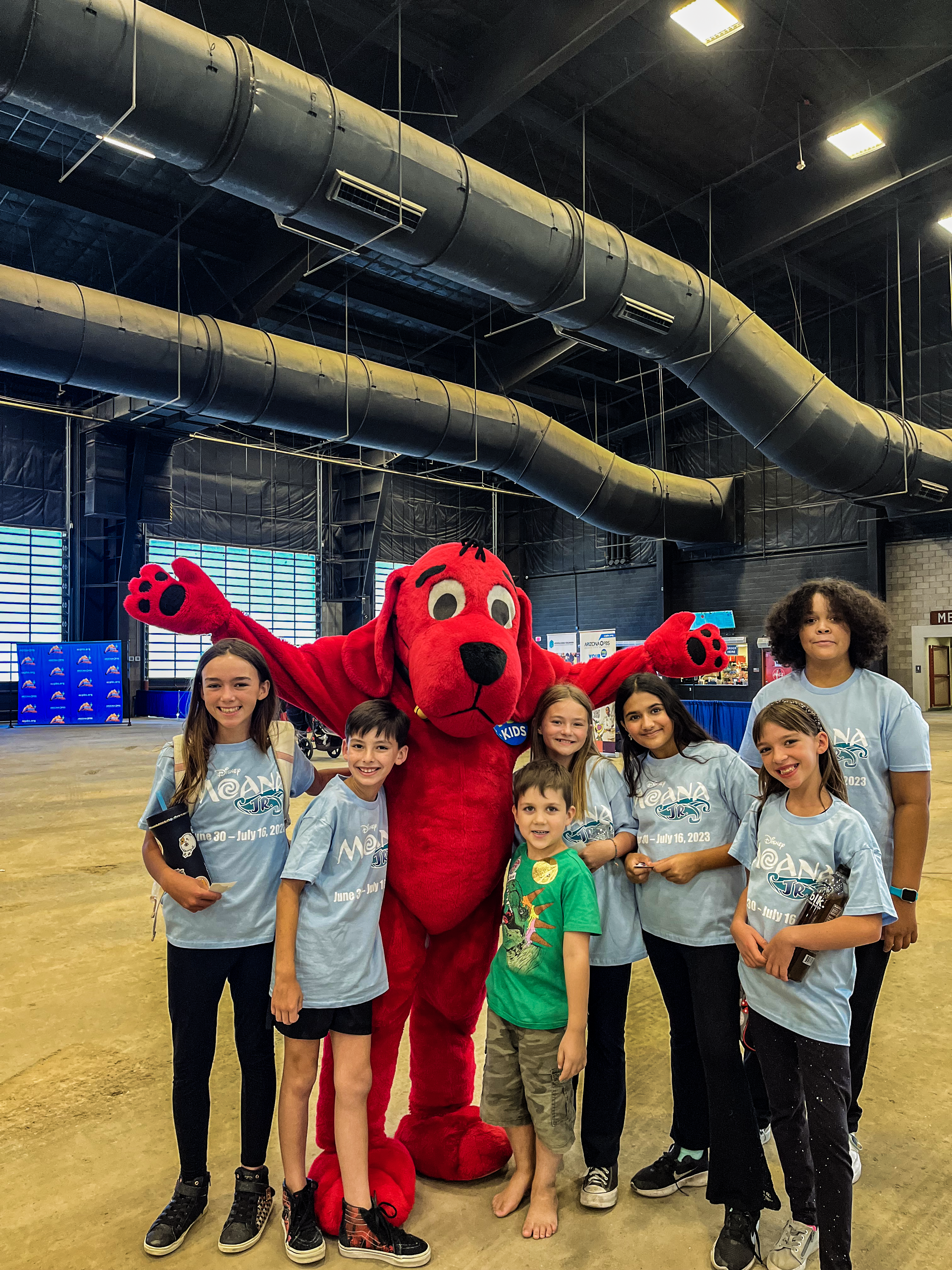 A group of children pose for a photo with Clifford the Big Red Dog.