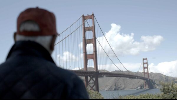David Rubenstein stands on a hill looking at the Golden Gate Bridge