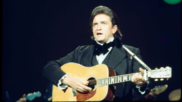 Johnny Cash plays a guitar and sings on stage