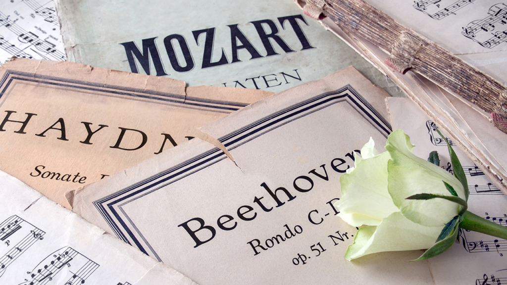 sheet music by Mozart, Haydn, and Beethoven with a white rose