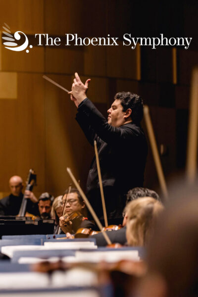 The Phoenix Symphony performing on stage with the conductor's arms raised, his baton clenched tightly in his hand