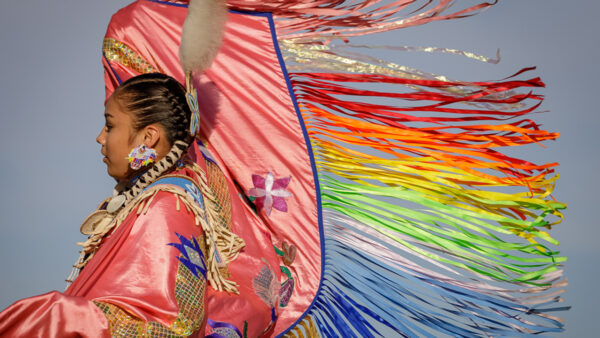 Indigenous person in rainbow regalia