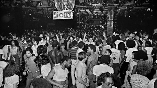 A black and white image of a dance hall packed with dozens of people enjoying disco