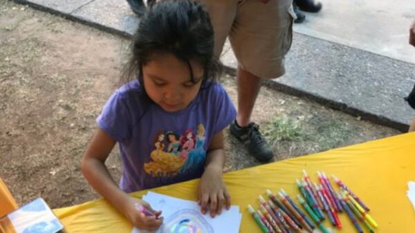 A young girl colors a drawing with markers