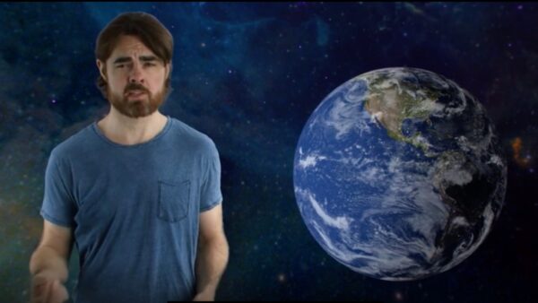 A scientist stands next to a large picture of planet Earth