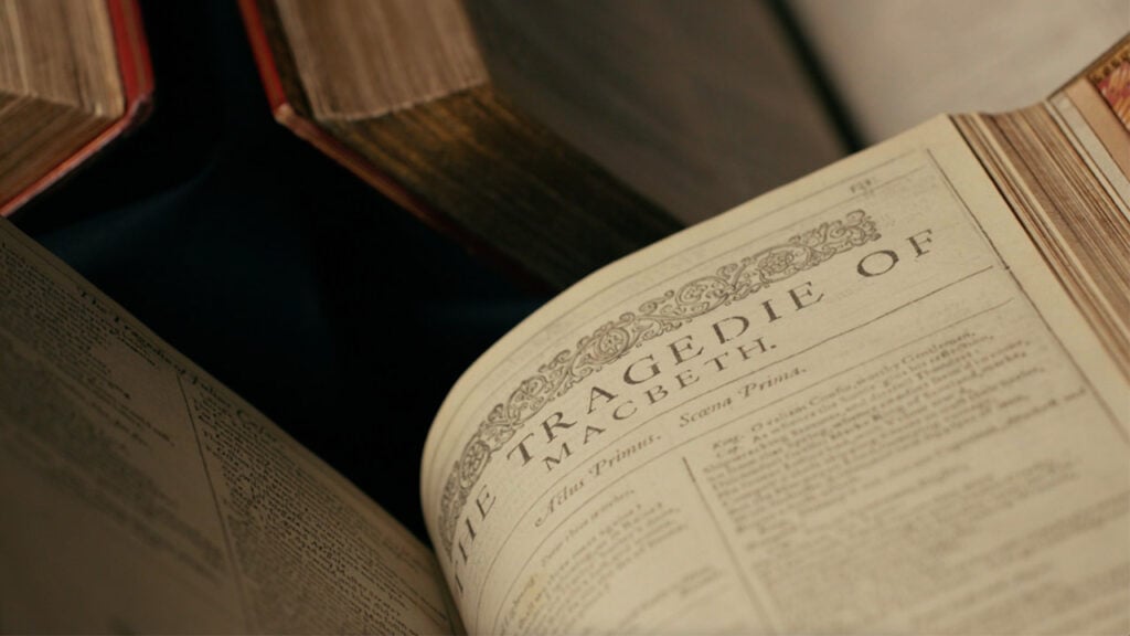 The first page of the play "Macbeth" in Shakespeare's First Folio with an ornate scroll work image above its title reading: The Tragedy of Macbeth