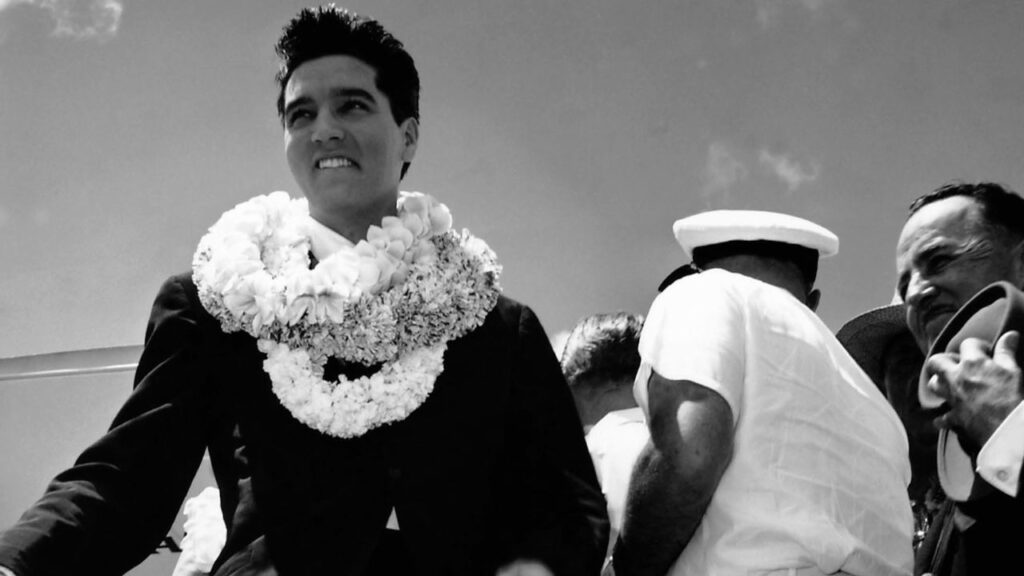 Elvis Presley wearing leis around his neck in Hawaii