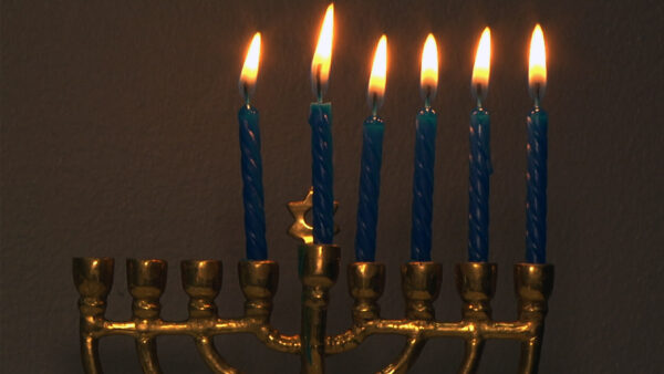 A menorah shines with six candles alight