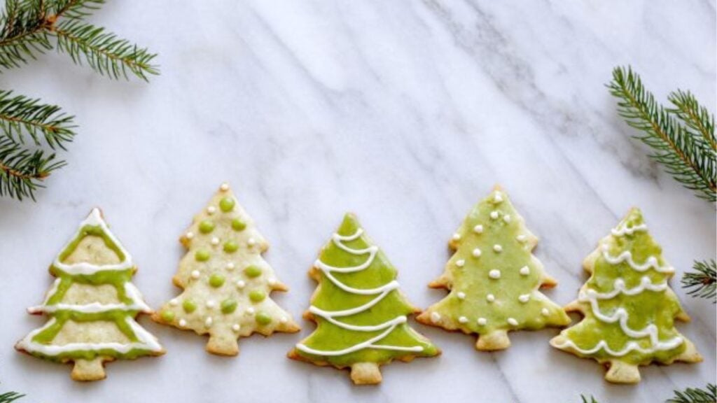 Five green Spruce Tree Shortbread cookies rest on a marble counter