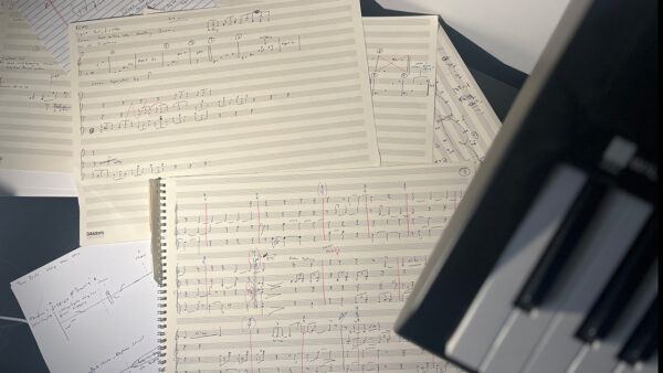 handwritten sheet music and the corner of a keyboard