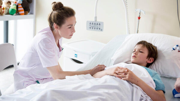 Nina, a nurse, leans on the bed of sick patient, a young boy